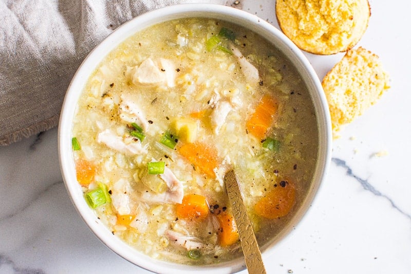 Instant pot chicken and rice soup in a bowl with corn muffins for serving.