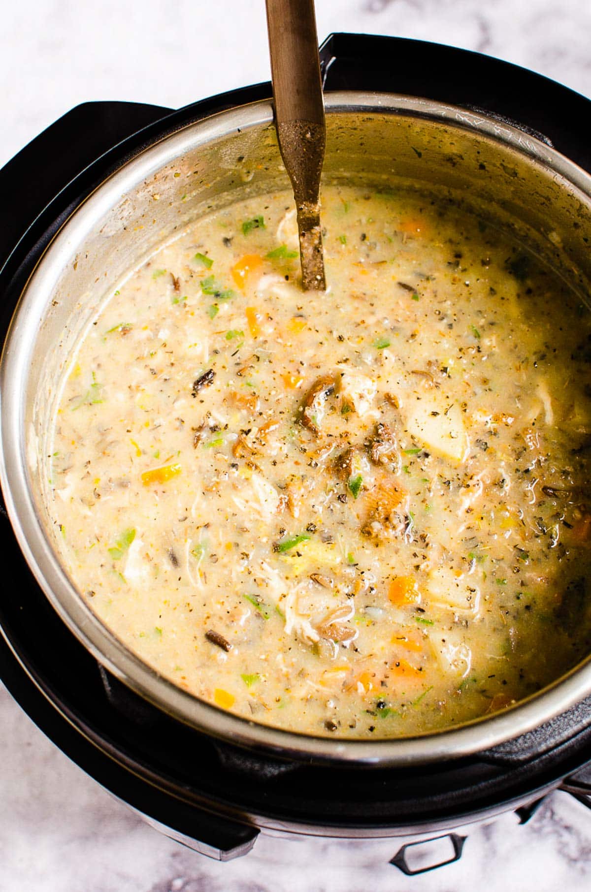 Instant Pot chicken wild rice soup with ladle inside the pot.