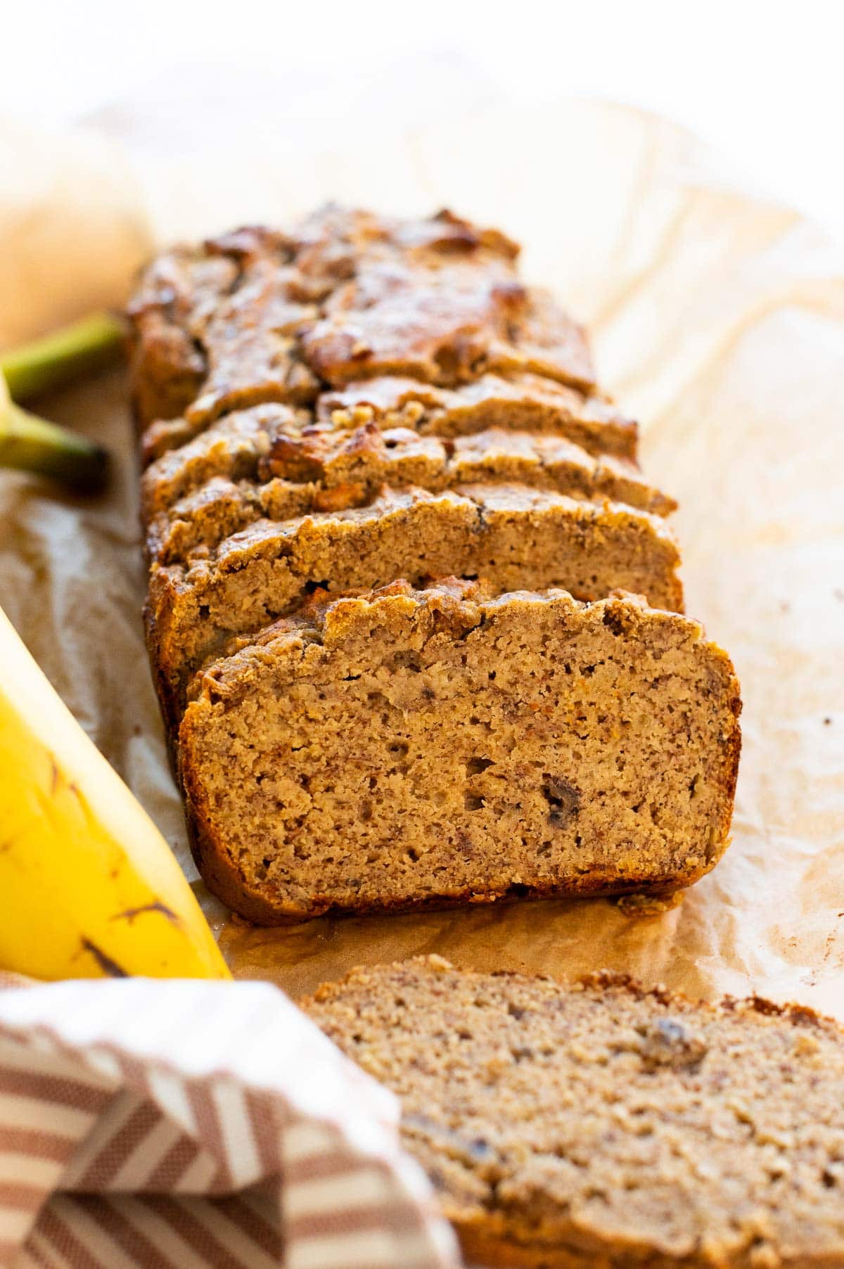 Sliced coconut flour banana bread loaf on parchment paper.