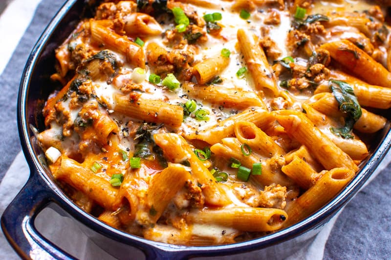 Ground turkey pasta bake topped with cheese in baking dish.
