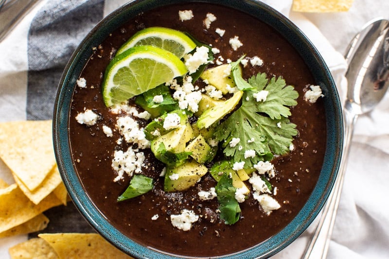 Instant pot black bean soup in a bowl with spoon and chips near it.