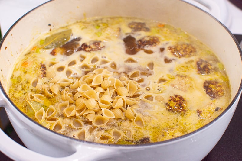 pasta boiling with meatballs in white pot