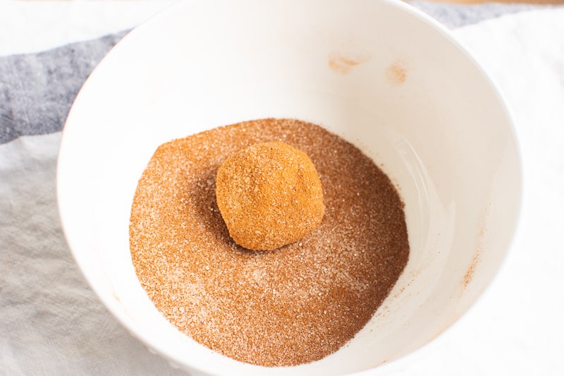 rolling almond flour snickerdoodle cookies in cinnamon sugar