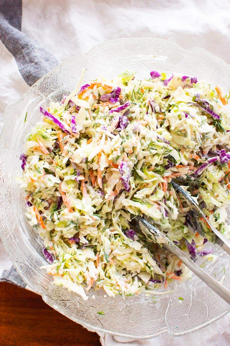 Healthy coleslaw recipe in a bowl with serving tongs.