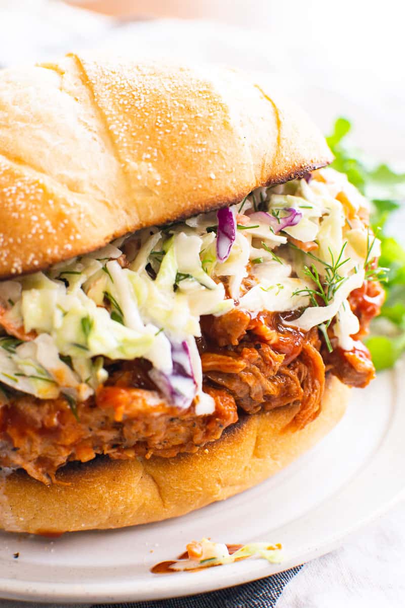 Instant Pot pulled pork on a sandwich bun with coleslaw.