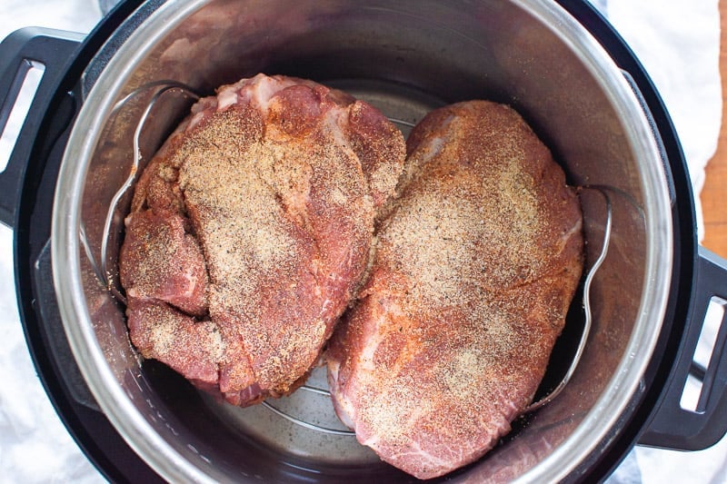 Two seasoned pork roasts on a trivet inside Instant Pot. 
