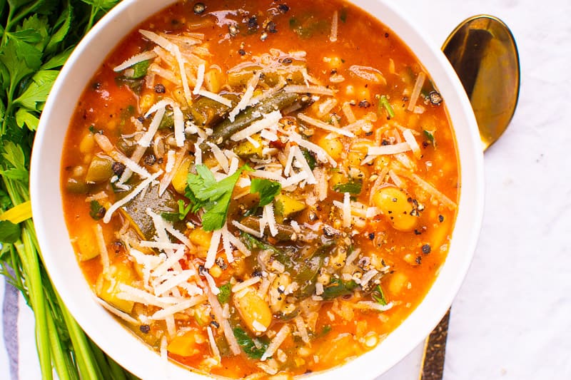 Minestrone Soup in white bowl garnished with parmesan cheese