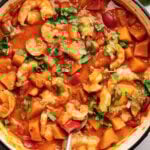 Thai shrimp curry garnished with cilantro in a skillet.