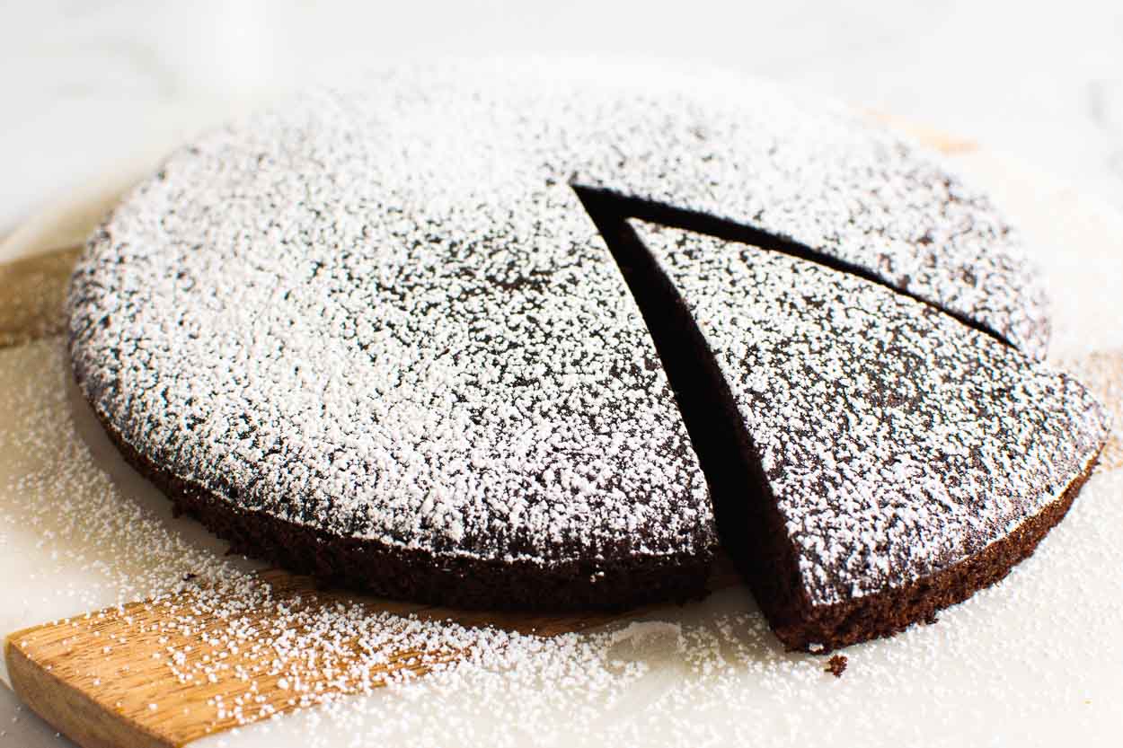 Almond flour chocolate cake dusted with icing sugar and slice.