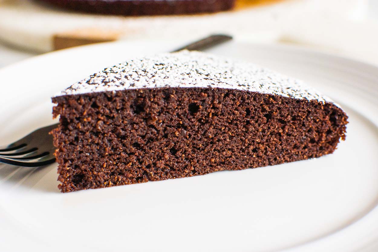 A slice of gluten free chocolate cake on a plate with fork.