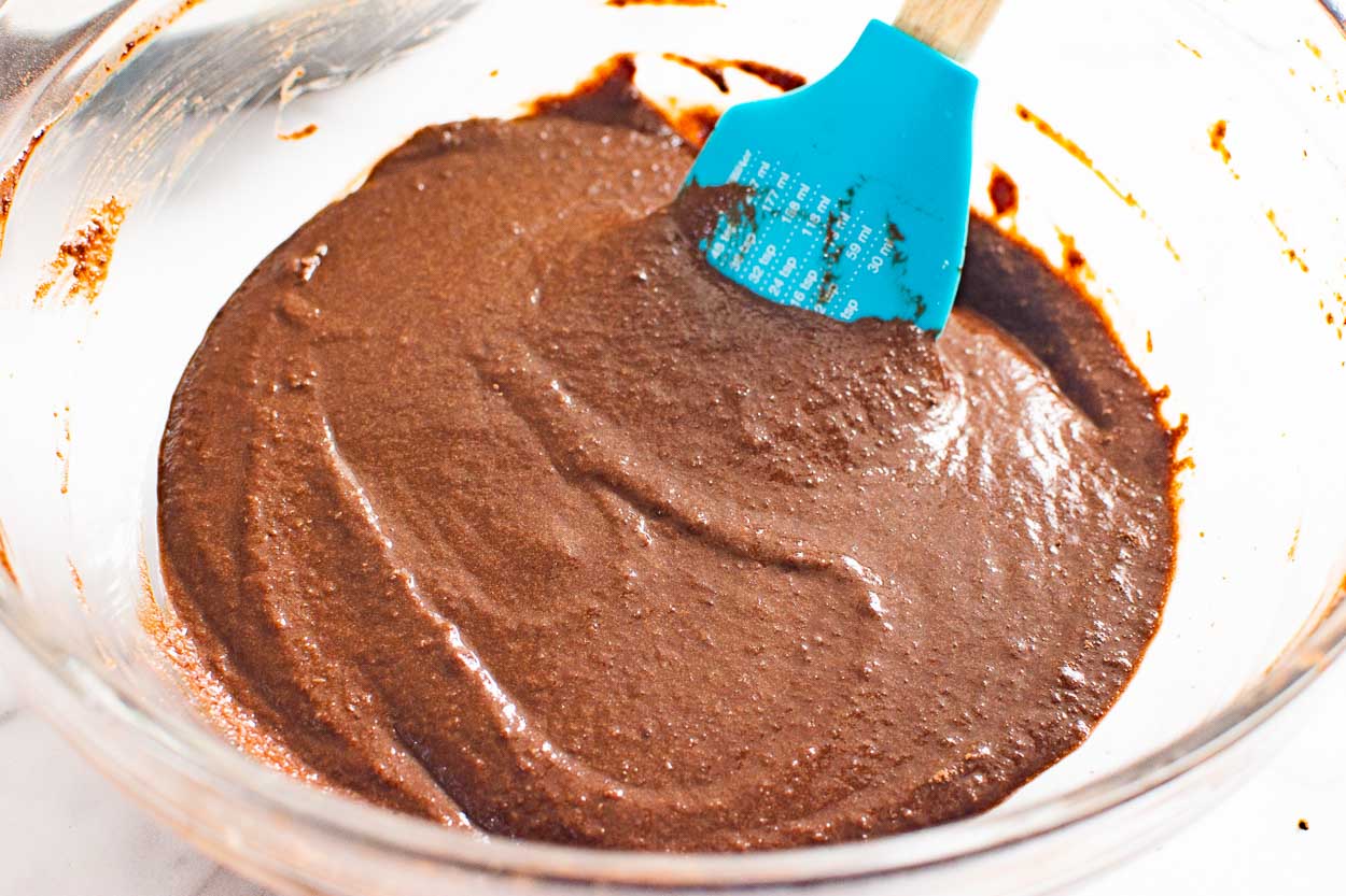 Chocolate cake batter being mixed with spatula.
