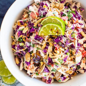 Thai chicken salad recipe served in white bowl and blue towel nearby.