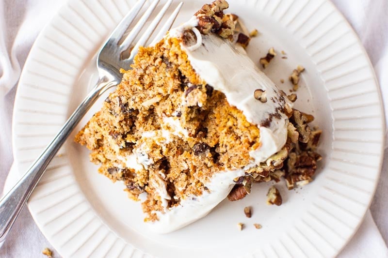 Slice of gluten free carrot cake on white plate with a fork.