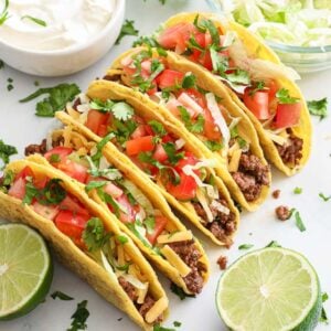 Ground Beef Tacos lined up with toppings