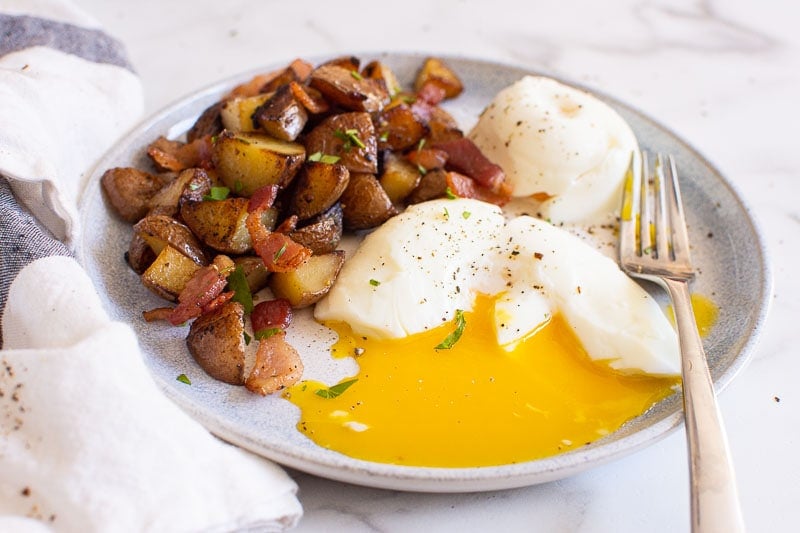 perfectly poached instant pot egg with breakfast potatoes on a plate