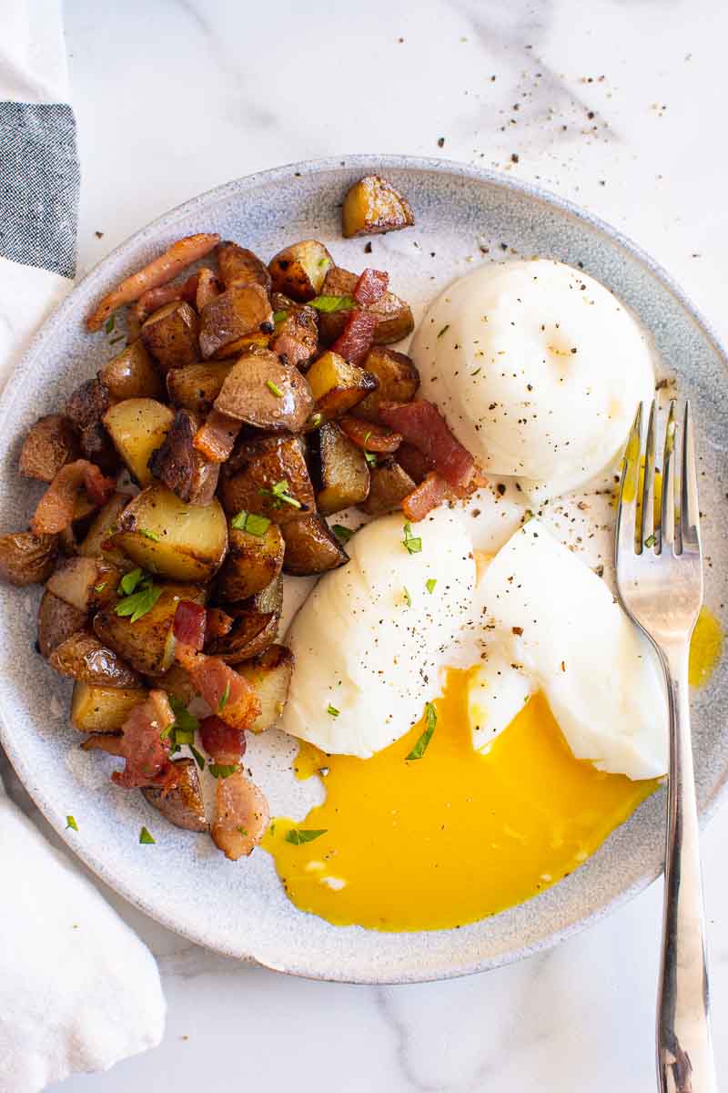 Instant Pot poached eggs with breakfast potatoes garnished with pepper.