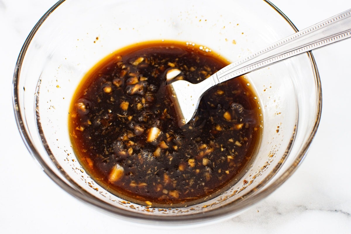 Brown sugar, soy sauce, oil, vinegar, garlic and ginger in a bowl with fork.