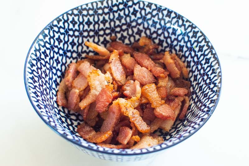 cooked bacon pieces in white blue bowl
