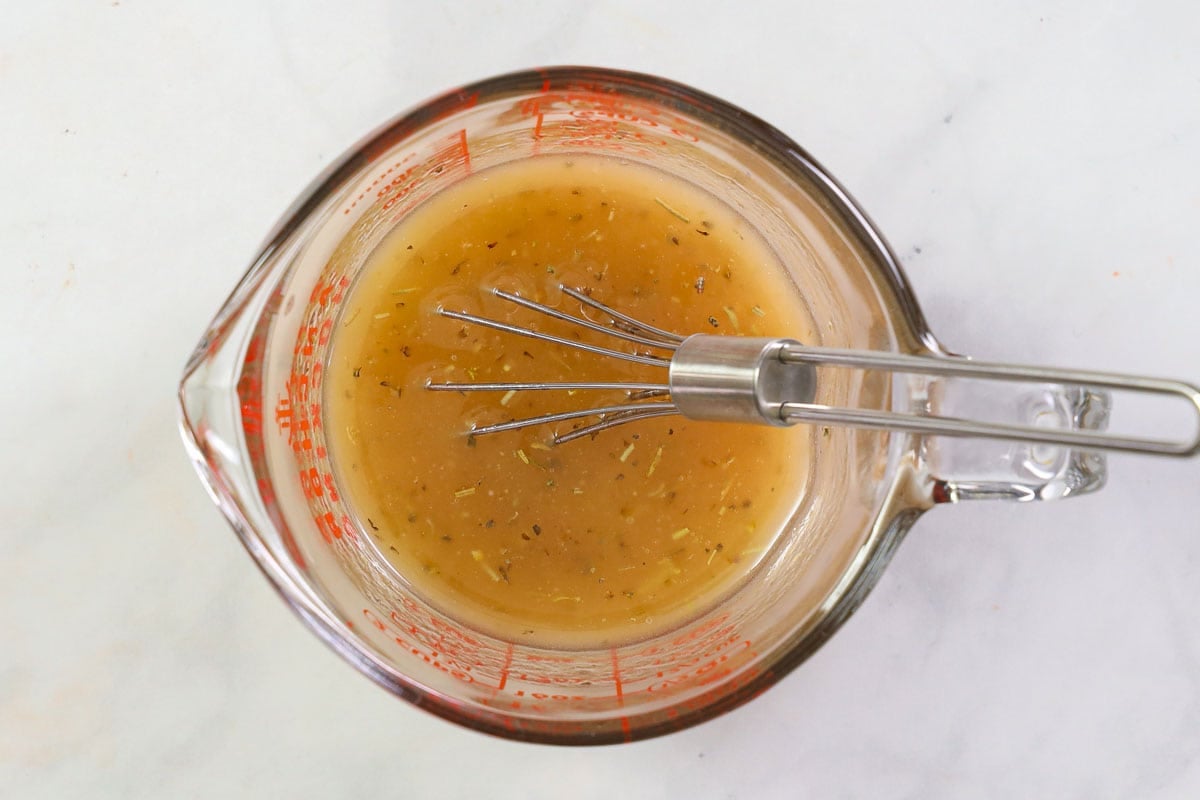 Whisking homemade dressing in a measuring cup.