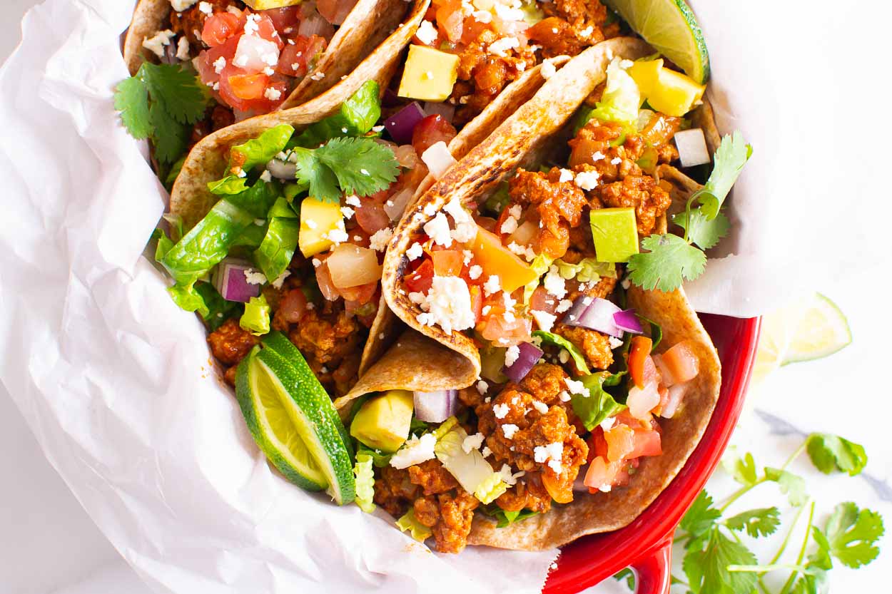 Ground turkey tacos served with toppings in red dish