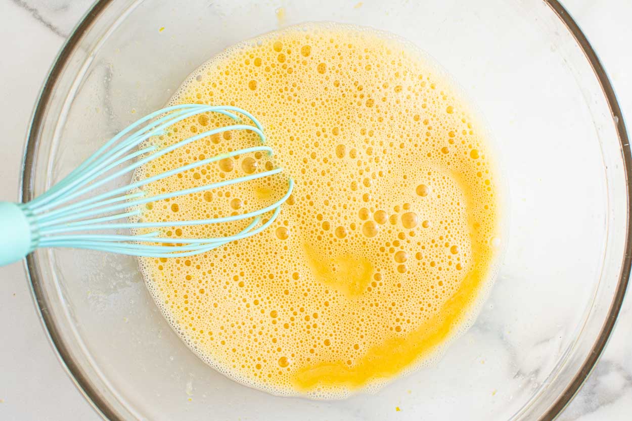 Whisked lemon bar filling in a glass bowl.