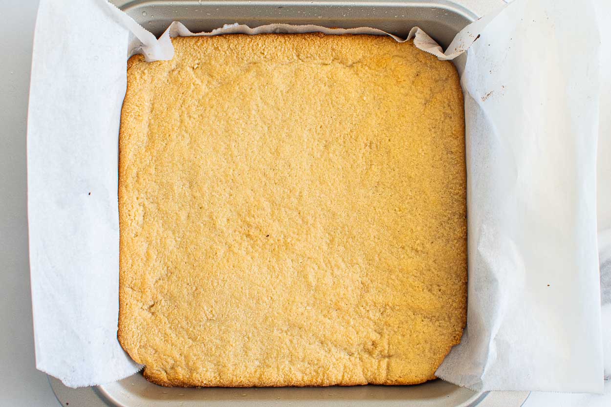 Baked almond flour crust in a square baking dish.