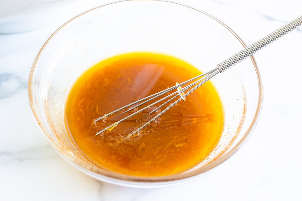 Salad dressing in glass bowl with a whisk.