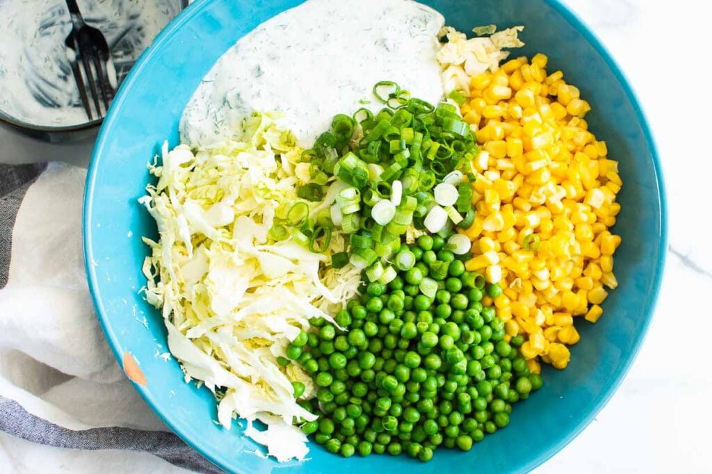 savoy cabbage, peas, corn, green onion and healthy ranch in blue bowl
