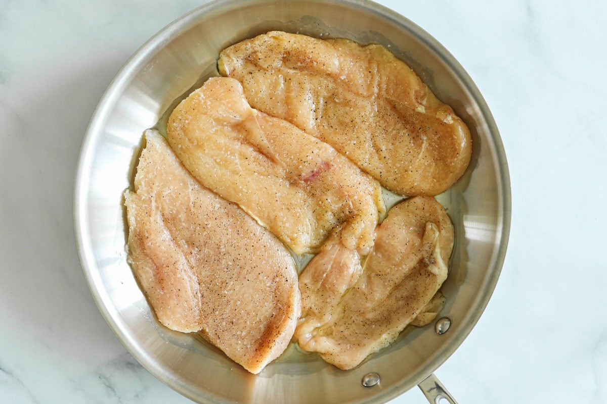 Cooking seasoned chicken breast cutlets in a skillet.