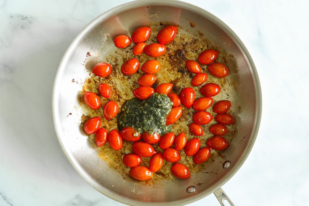 Cherry tomatoes and pesto in a skillet.