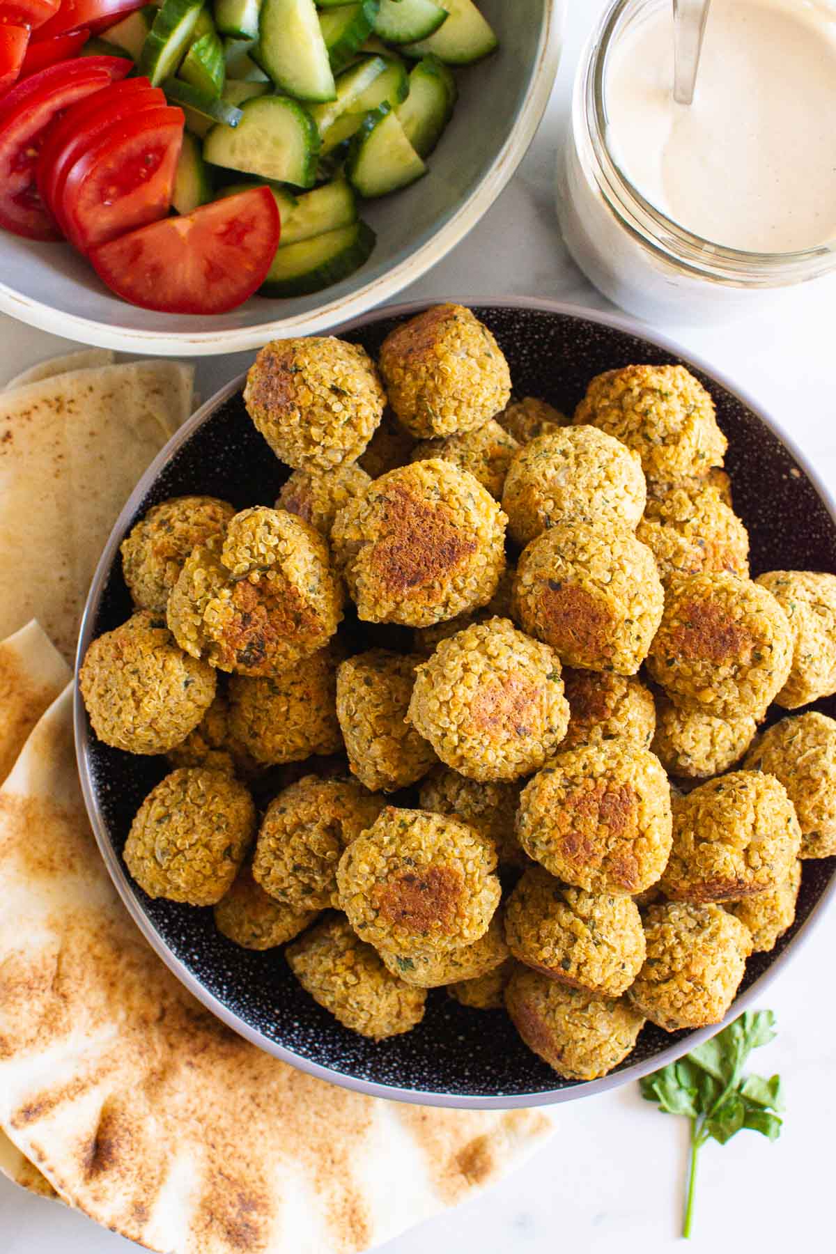 chickpea quinoa falafel piled in a bowl sauce and pita sandwich items