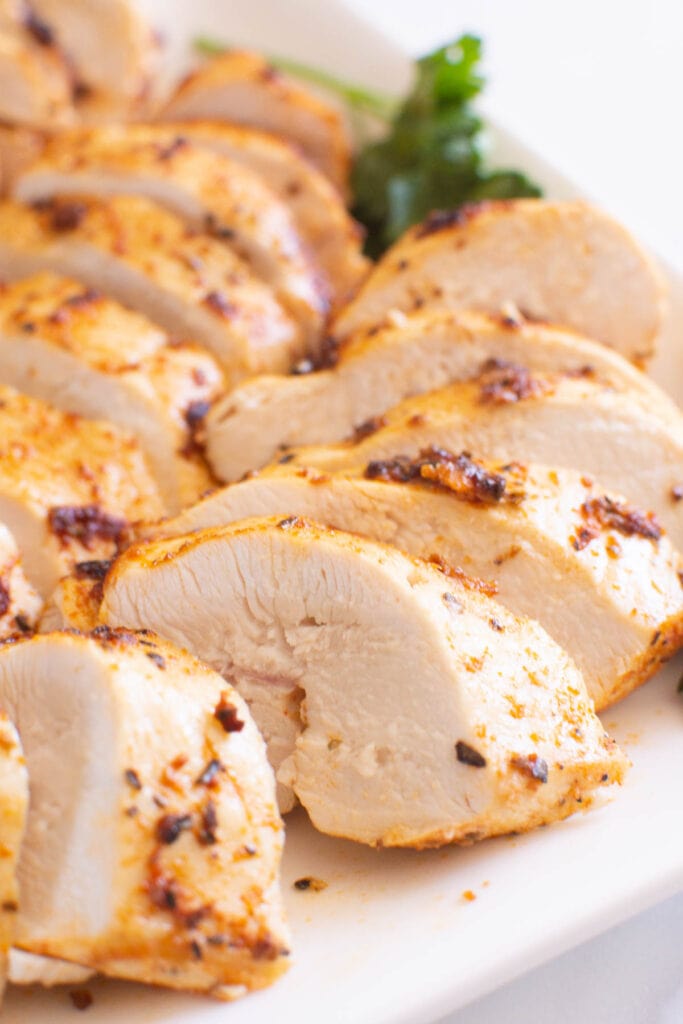 close up for air fryer chicken breast sliced on a plate with garnish