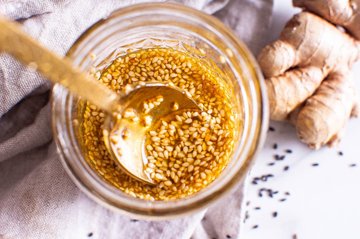 Jar with salad dressing and golden spoon.