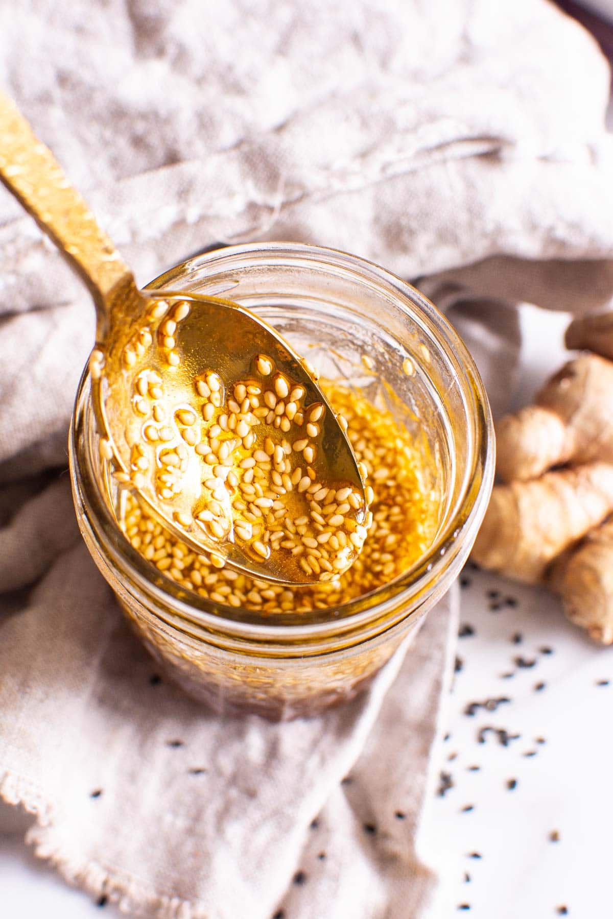 Asian salad dressing with golden spoon dipped into mason jar.