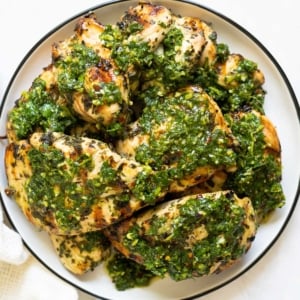 Chimichurri chicken thighs served with chimichurri sauce on a plate.