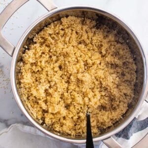 Fluffed cooked quinoa in a pot with fork.