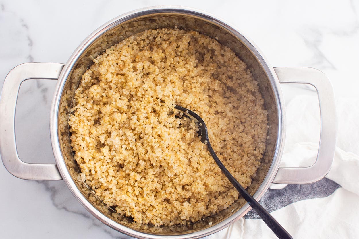 Cooked quinoa in a stove pot with fork.