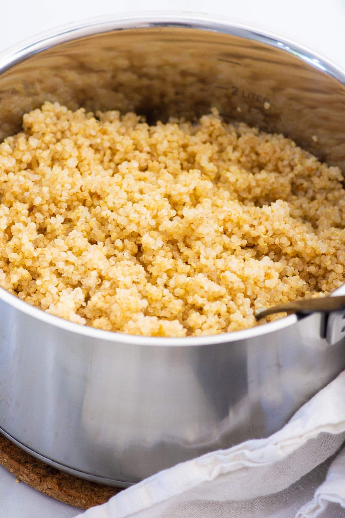 Cooked quinoa in a stove pot fluffed with a fork.