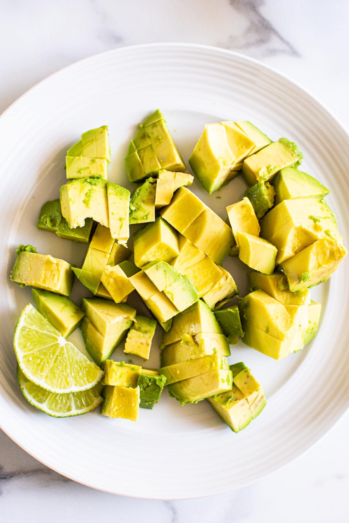 Diced avocado with lime on a plate.