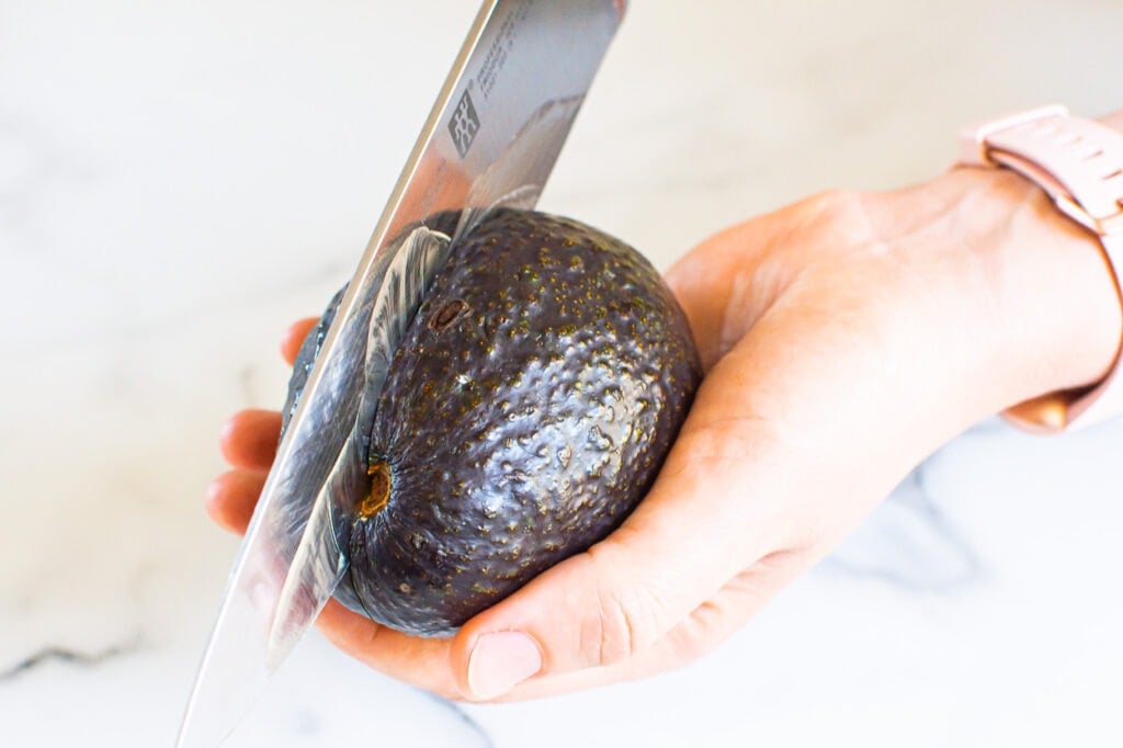 avocado with knife being cut
