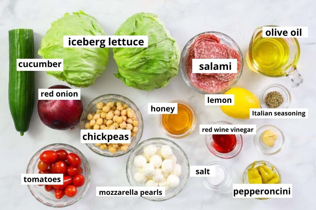 Iceberg lettuce, salami, chickpeas, mozzarella balls, tomatoes, red onion, cucumber, lemon, spices, honey, oil, vinegar, mustard.