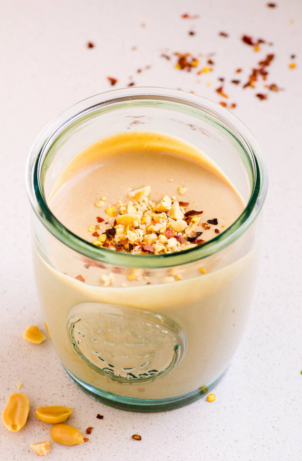 homemade peanut sauce in glass jar with peanuts and chili pepper