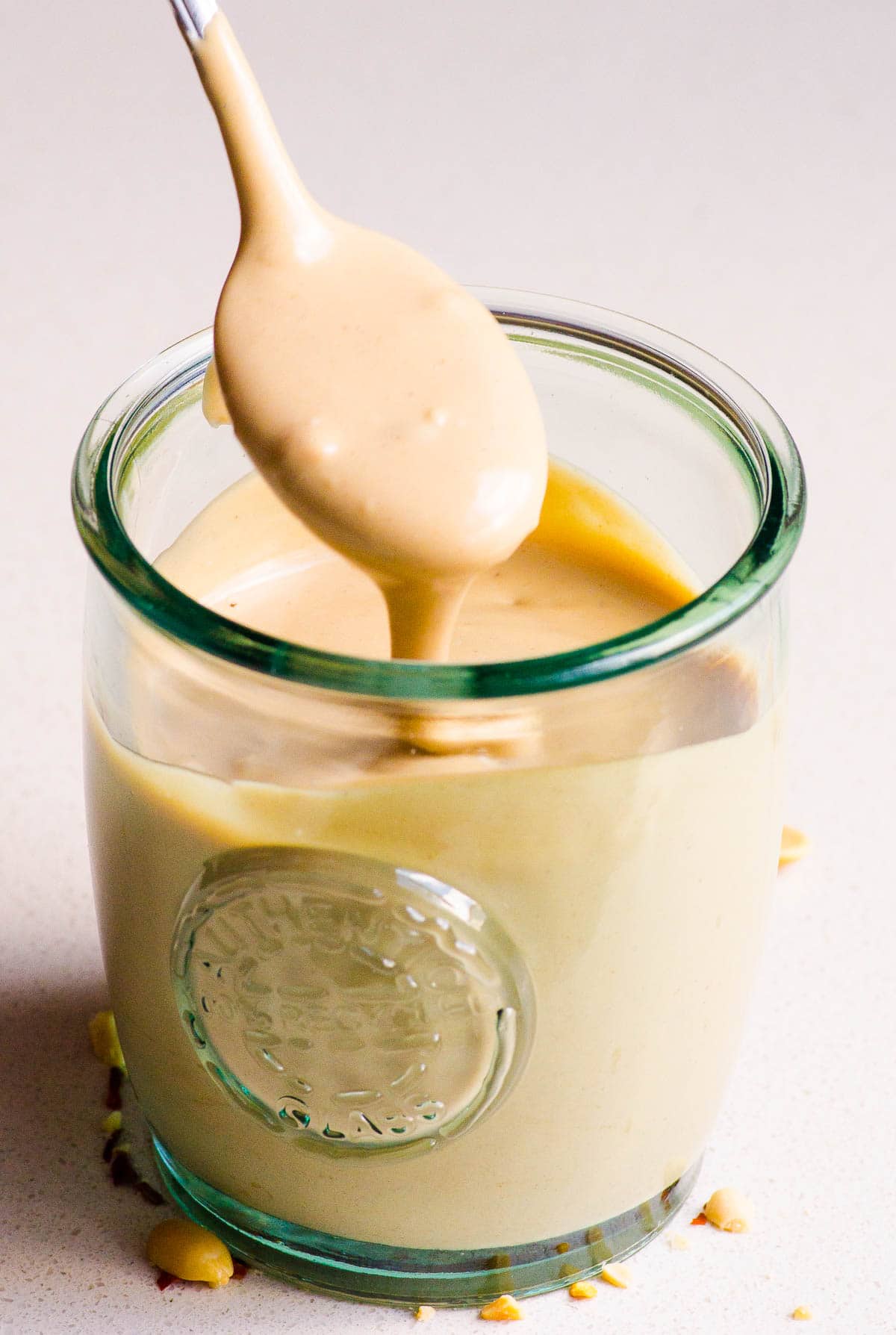 peanut sauce dripping off of spoon into glass jar