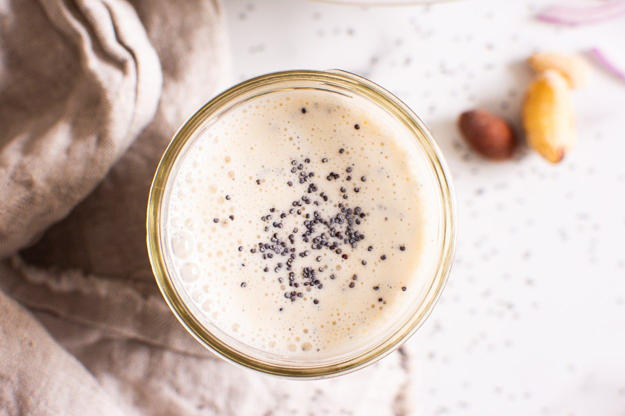 Poppy seed dressing in small jar with poppy seeds on top.