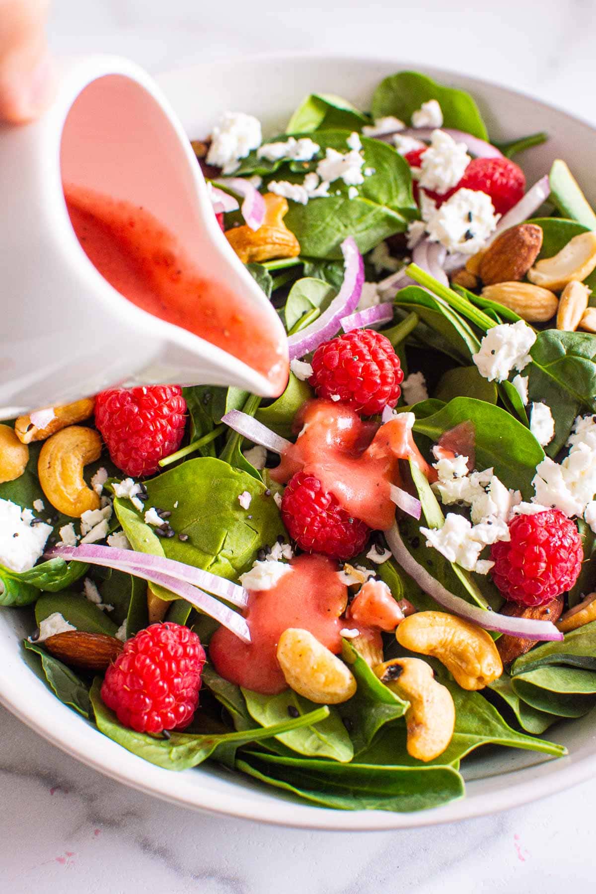 raspberry vinaigrette recipe being poured onto a salad