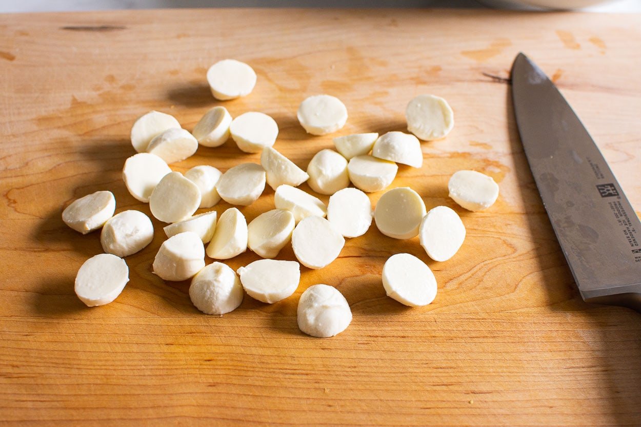 Chopped fresh mozzarella balls on cutting board.