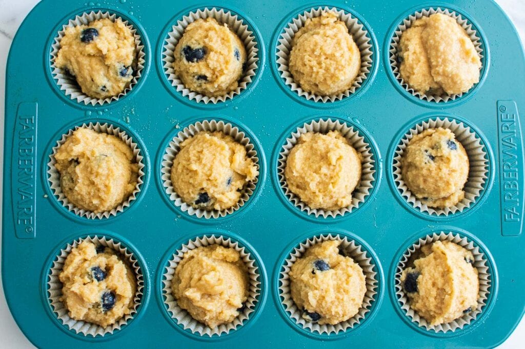unbaked muffins with almond flour and blueberries in a blue cupcake pan