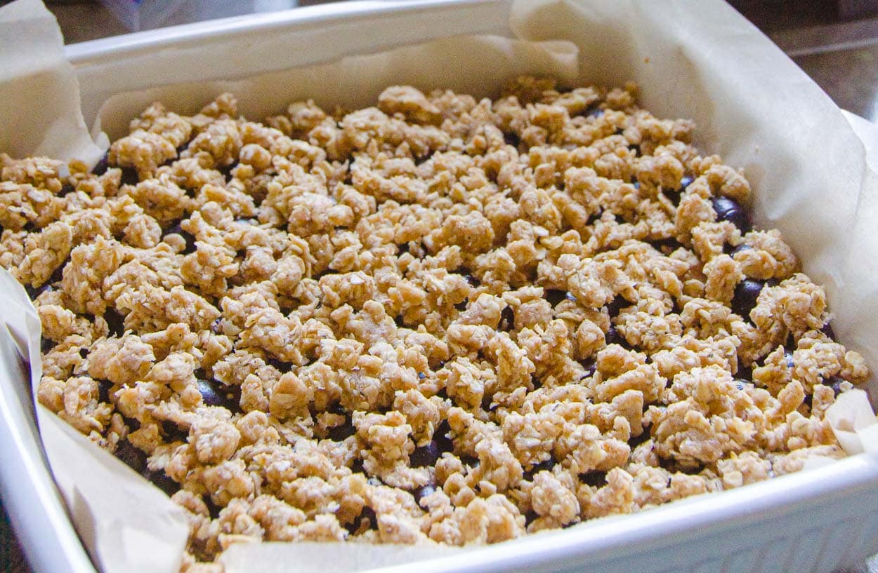 Blueberry crumbles spread over the blueberry filling in a baking dish.