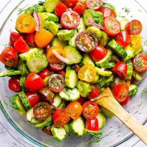 cucumber and tomato salad in a bowl with a spoon