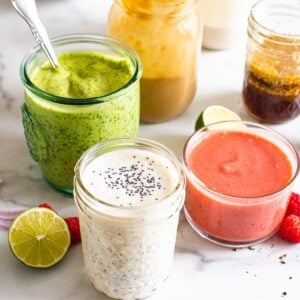 Six healthy homemade salad dressings in mason jars.